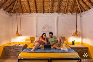 a man and woman sitting on a bed with a laptop at Zostel Hampi, Gangavathi in Hampi