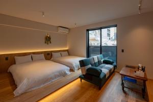 a bedroom with two beds and a couch and a chair at Hotel Arina HakataTaihaku in Fukuoka