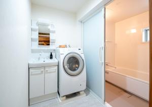 a bathroom with a washing machine and a sink at simAsim Cottage Kouri in Nakijin