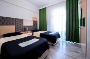 a hotel room with two beds and green curtains at seyir royal in Kayseri