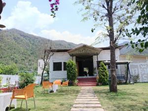 a white house with chairs in the yard at Petals Cafe & Resort in Rājpur