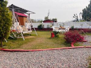 a yard with a swing and a house at Petals Cafe & Resort in Rājpur