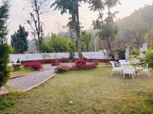 a garden with tables and chairs in a yard at Petals Cafe & Resort in Rājpur