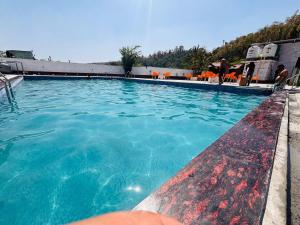 a swimming pool with blue water and orange chairs at Petals Cafe & Resort in Rājpur