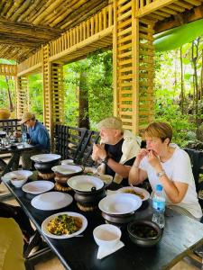 a group of people sitting at a table with food at Materuni Homes in Moshi