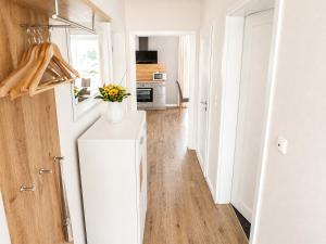 a white kitchen with a vase of flowers on a refrigerator at Reetdachhaus 3, inkl 2 Parkplätze in Fehmarn