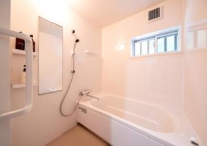 a white bathroom with a tub and a sink at simAsim Cottage Kouri in Nakijin