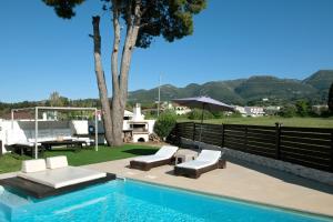 a swimming pool with two lounge chairs and an umbrella at Beach Villa Christina by PosarelliVillas in Acharavi