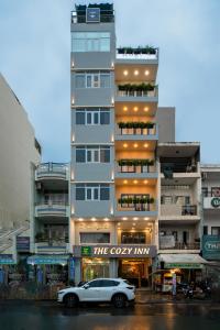 a white car parked in front of a building at The Cozy Hotel in Ho Chi Minh City