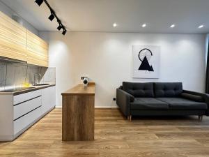 a living room with a black couch and a kitchen at Kamanina Lux Apartment in Odesa +6 photos