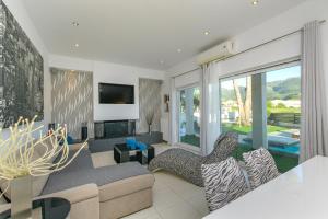 a living room with a couch and chairs and a tv at Beach Villa Christina by PosarelliVillas in Acharavi