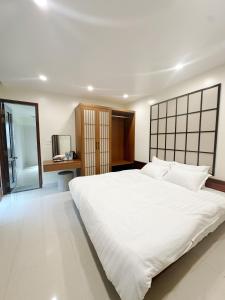 a bedroom with a large white bed and a desk at SAM Homestay and Cafés in Thôn An Hòa