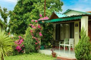 a cottage with a table and chairs in a garden at Entire Farm house in Jim Corbett with staff and cook in Rāmnagar +14 photos
