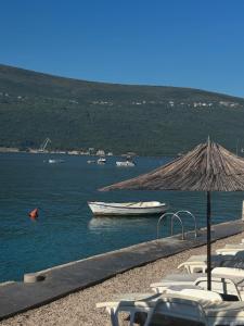 a boat in the water with a straw umbrella at Kuća za odmor in Đenovići