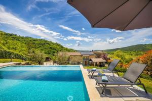 a swimming pool with two chairs and an umbrella at Villa Palazza in Pazin