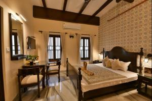 a bedroom with a bed and a desk and a table at Eennra Oiitijhyya in Kolkata
