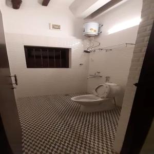 a bathroom with a toilet and a window in it at Eennra Oiitijhyya in Kolkata