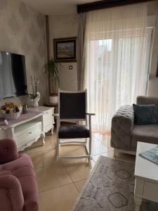 a living room with a tv and a couch and a chair at LuxHouseNiksic in Nikšić