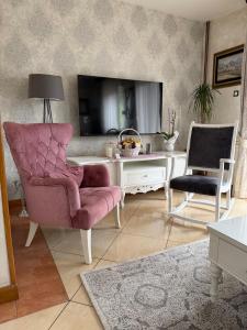 a living room with a pink chair and a tv at LuxHouseNiksic in Nikšić