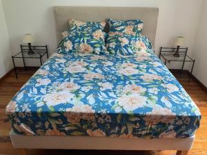 a bed with a blue floral bedspread and two night stands at Casa Defranchi in Sant Andrea di Bozio