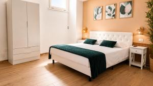 a bedroom with a white bed with a green blanket at Almarea Apartments in Santa Domenica