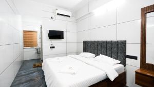 a white bedroom with a bed and a television at Sreebhadra Residency in Chavara