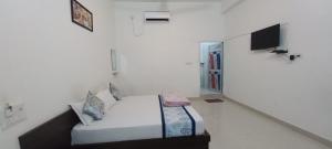a white room with a bed and a tv at Amrit hotel & resort in Nārāyanpur