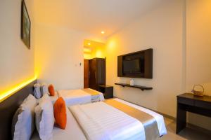 a hotel room with two beds and a tv at Alqueby Hotel Bandung in Bandung