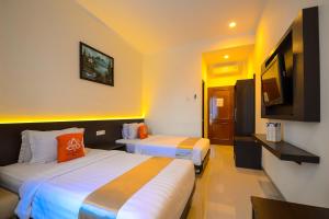 a hotel room with two beds and a flat screen tv at Alqueby Hotel Bandung in Bandung