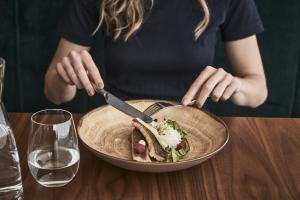 a woman sitting at a table with a plate of food at Falkensteiner Balance Resort Stegersbach l Adults Only in Stegersbach