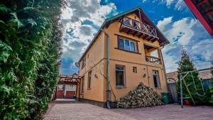 a yellow house with a pile of fire wood at Pensiunea Hanna in Braşov