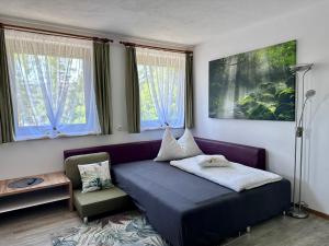 a bedroom with a bed and a couch and windows at Ferienwohnung Petritz in Velden am Wörthersee