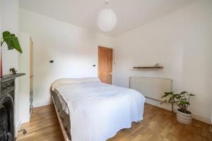 a white bedroom with a bed and a fireplace at Victorian Terrace near Uni sleeps 6 Garden in Reading