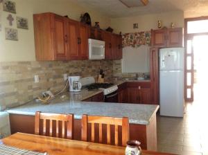 a kitchen with wooden cabinets and a white refrigerator at Casa de la Tortuga in Zihuatanejo