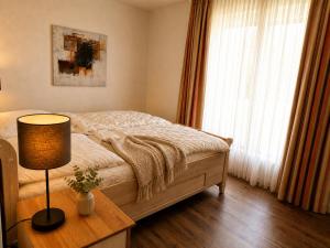 a bedroom with a bed and a table with a lamp at Reetdachhaus 6, inkl 2 Parkplätze in Fehmarn