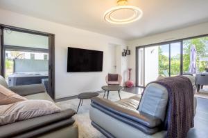 a living room with a couch and a tv at Sitelles Lodge Cube avec spa in Concarneau