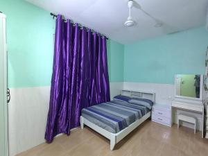 a bedroom with purple curtains and a bed and a mirror at Heena in Kendhoo