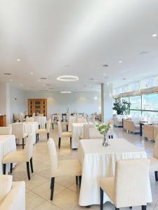a dining room with white tables and white chairs at Aurelis Hotel in Bërxull