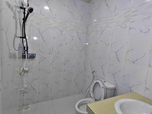 a white bathroom with a toilet and a sink at Heena in Kendhoo