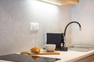 a kitchen counter with a coffee cup and croissants on a cutting board at George Studios in Yénion +87 photos