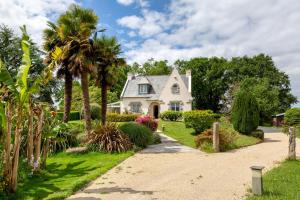 a white house with palm trees and a driveway at Chez Coco in Trégunc