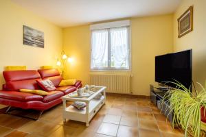 a living room with a red couch and a flat screen tv at Chez Coco in Trégunc