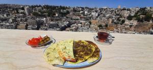 a table with two plates of food and a drink at Citadel Boutique Hotel in Amman