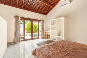a bedroom with a bed and a balcony at Tropical Villas Complex in Jimbaran