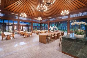 a dining room with tables and chairs and chandeliers at MĀUA OLEA Ubud by Swiss-Belhotel in Ubud