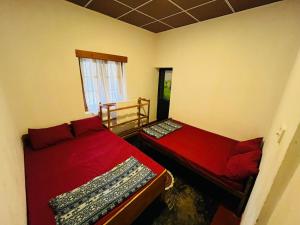 two beds in a room with red sheets and a window at Lodgepole Pine Resorts in Welimada