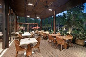 a restaurant with tables and chairs on a wooden deck at MĀUA OLEA Ubud by Swiss-Belhotel in Ubud