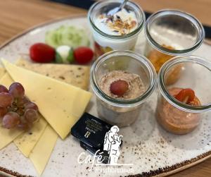 a plate of food with jars of food and cheese at Hotel Bären in Schramberg