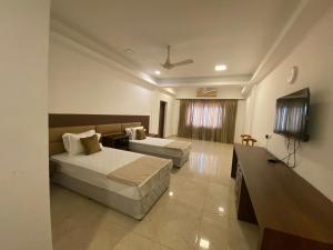 a hotel room with a bed and a tv at The King's Hotel in Tuticorin
