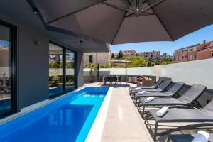 an outdoor swimming pool with lounge chairs and an umbrella at Casa Seal by Briskva in Funtana